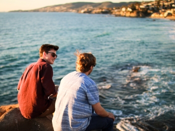 Two male friends at the beach talking