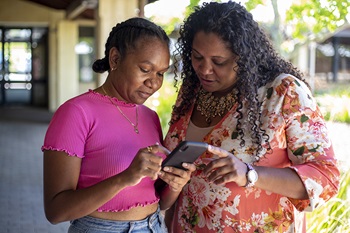 Two Aboriginal women looking at a smartphone together.