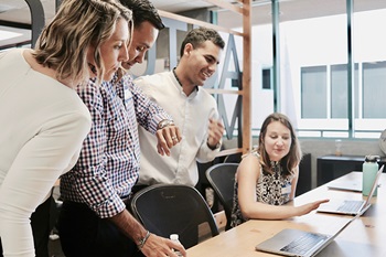 Office workers meeting around a laptop