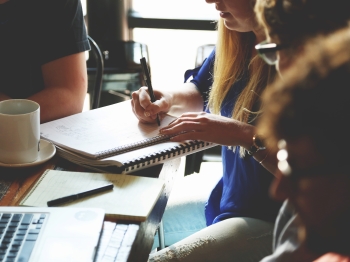 People sitting around a table writing in notebook