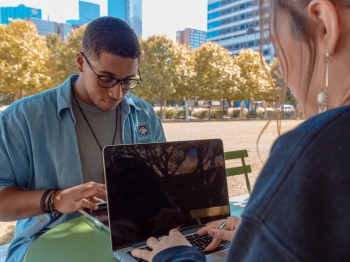 A young man and young woman on their computers 